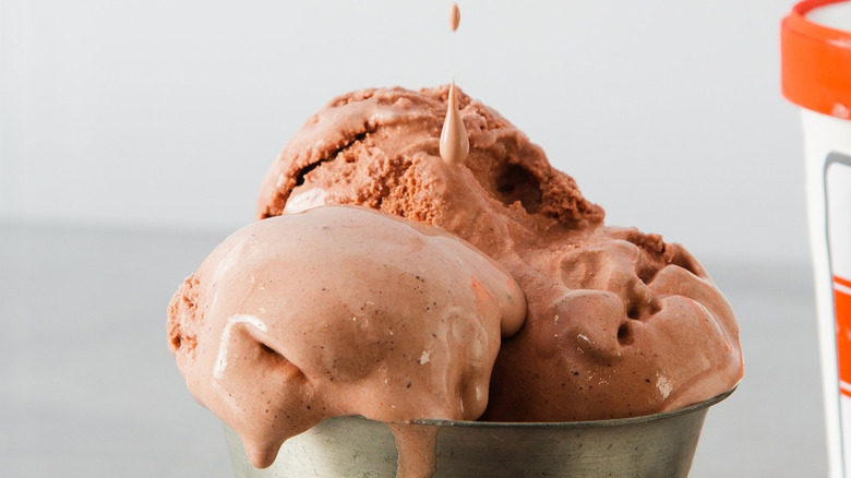 Metal sundae dish with scoops of ice cream next to pint of ice cream