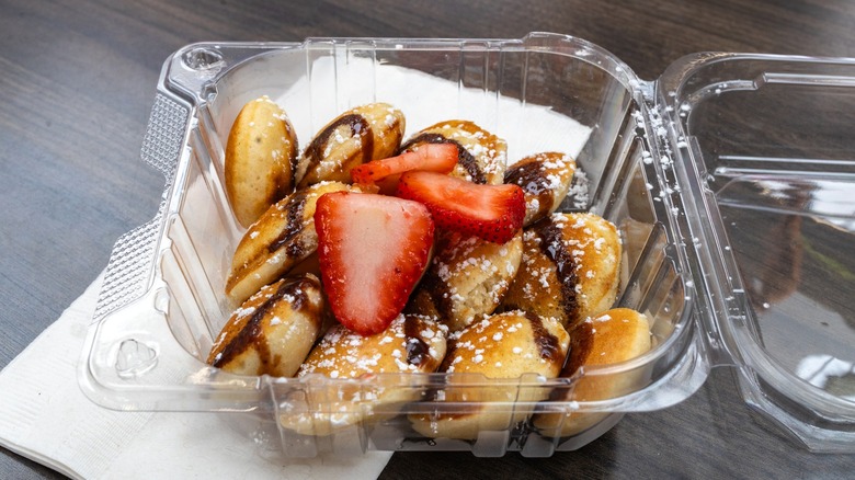 Plastic takeout box with mini pancakes and strawberries