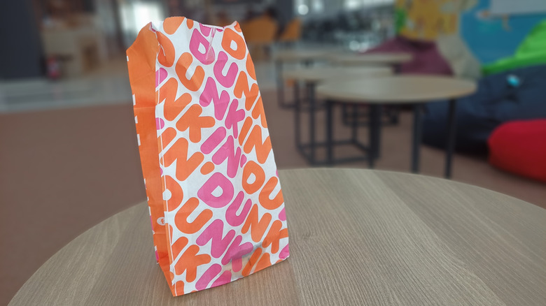 Dunkin' branded bag on table, blurred background