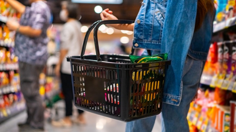 A shopper holds a basket at a grocery store