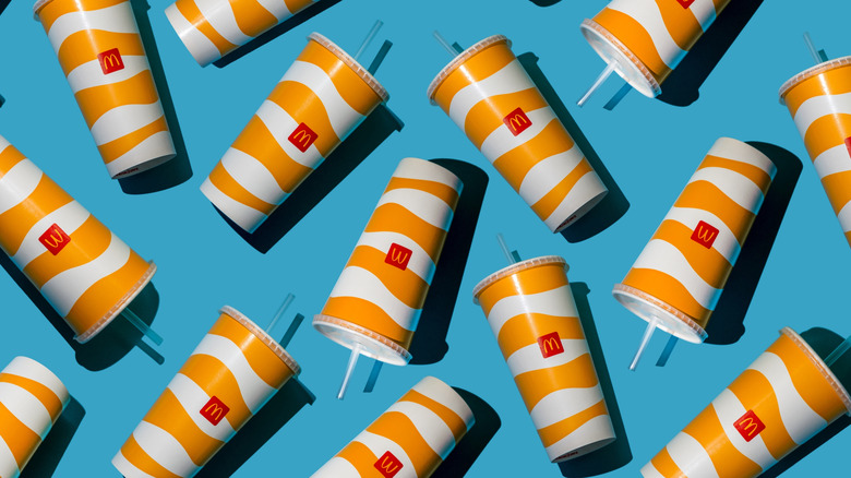Scattered Mcdonald's beverage cups with logo on blue background