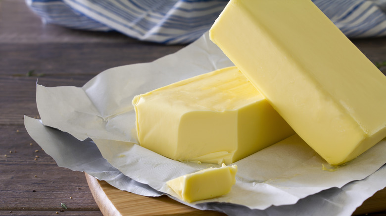 Golden butter in wrapper on a wooden board